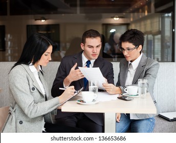 Young Business People Working Over A Paperwork And Drinking Coffee