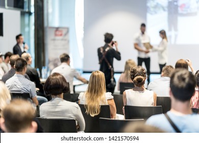 Young business team receiving award prize at best business project competition event. Business and entrepreneurship award ceremony theme. Focus on unrecognizable people in audience. - Shutterstock ID 1421570594