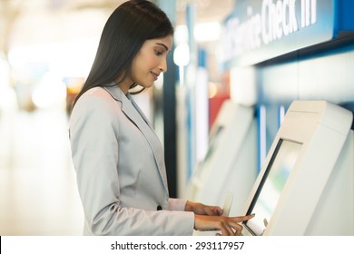 Young Business Traveller Using Self Service Check In Machine At Airport