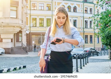 Young business woman in city looking at her wristwatch