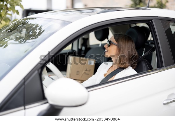 Young business woman\
driving car with a parcels on a passenger seat. Online shopping and\
delivery concept