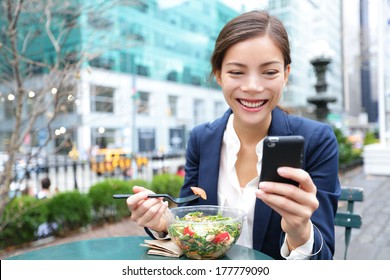 Young business woman eating salad on lunch break in City Park living healthy lifestyle working on smart phone. Happy smiling multiracial young businesswoman, Bryant Park, manhattan, New York City, USA - Powered by Shutterstock