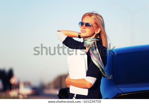 Young\
business woman with financial papers at the\
car