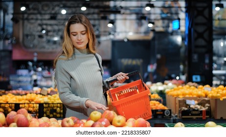 Young Business Woman Girl Buyer Client Blonde Lady Consumer Stands In Shop Near Counter With Fruits In Grocery Store Supermarket Choosing Juicy Ripe Apples For Juice Diet Food Buying Puts In Basket