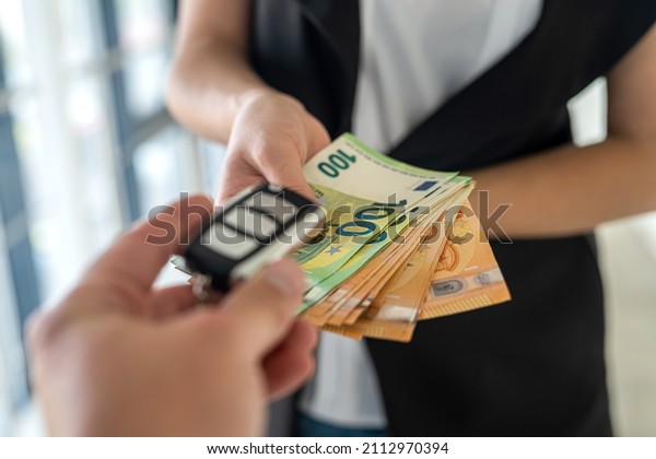 a young\
business woman is given car keys and she is euros for a car. The\
concept of buying a car. Business\
concept