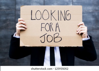 Young business woman holding sign Looking for a job - Shutterstock ID 125935052