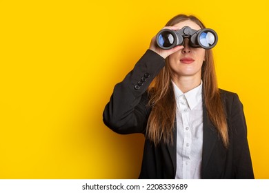 young business woman looking through binoculars on a yellow background. - Powered by Shutterstock