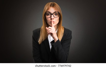 Young business woman making silence gesture on dark background