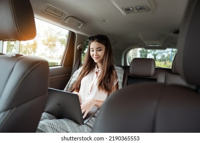 Young business woman with a modern laptop sitting in the back seat of luxury car. Successful startup, distance working, female boss concept. - Shutterstock ID 2190365553