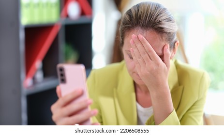 Young Business Woman On Phone Embarrassed By Receiving Sms With Bad News. Unhappy Woman Having Problems With Electronic Device In Office