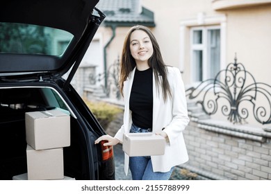 Young Business Woman Picking Up Parcels From A Car Trunk, Coming Home By Car.