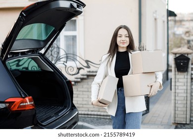 Young Business Woman Picking Up Parcels From A Car Trunk, Coming Home By Car