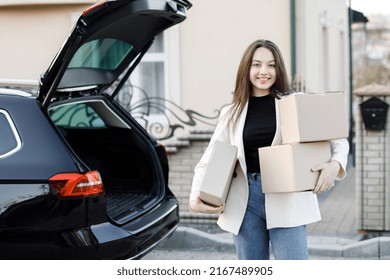 Young Business Woman Picking Up Parcels From A Car Trunk, Coming Home By Car