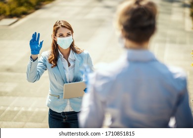 Young Business Woman With Protective Mask On Her Face Is Going To Work At They Say Hello To Her Friend During Covid19 Pandemic.