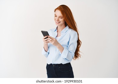Young business woman reading message on smartphone and smiling, social networking while standing over white background