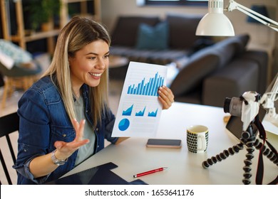 Young business woman recording video for her vlog shows papers with graphs