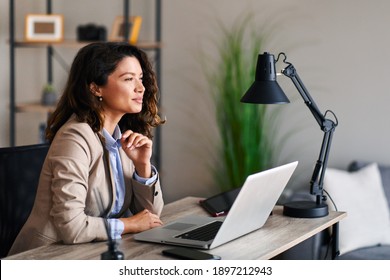 Young business woman sits at a desk in the office and looking away