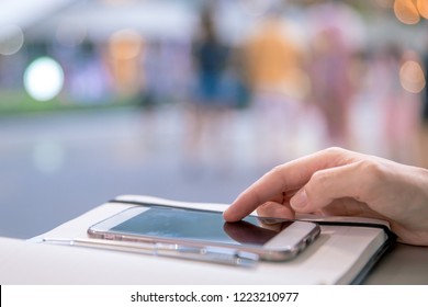 Young business woman sitting at table in cafe and writing in notebook. Using mobile phone to sms and sending messege. - Shutterstock ID 1223210977