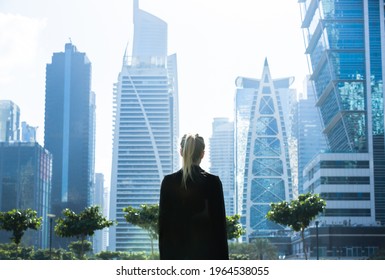 Young business woman standing alone looking at the modern downtown high-rises city view.  - Shutterstock ID 1964538055