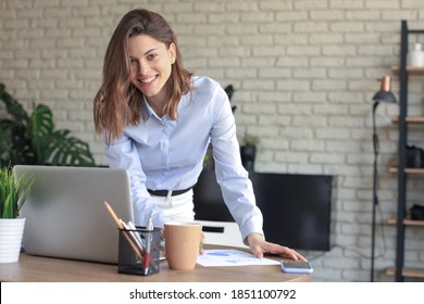 Young Business Woman Standing In Her Home Office Writing Notes.