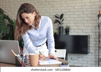 Young Business Woman Standing In Her Home Office Writing Notes.