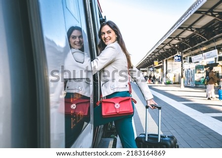 Young business woman standing on train door peeking out looking for somebody in railway station - Potrait of beautiful traveler woman getting on the train - Travelling concept