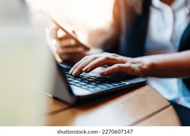 Young business woman or student sitting in cafe bar or restaurant and using smart phone and laptop computer. Close up shot on woman's hand. Beautiful creamy sunlight in background. Selective focus. - Shutterstock ID 2270607147