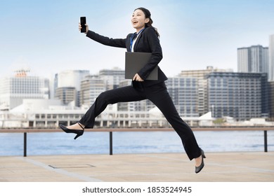 A Young Business Woman In A Suit Jumping With A Smile