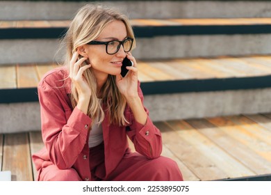 Young business woman talking on a mobile phone outside.