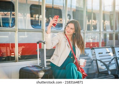Young business woman waiting for the train sitting at the waiting room of train station - Cheerful and happy traveler talking on the smartphone while waiting for the train