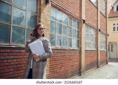 Young Business Woman Walking By A Vintage Old New Yourker Building With Papers In Arms Ready For A Professional Meeting At Office. Concept: Employee At Way At Meeting With Paperwork And Confidence