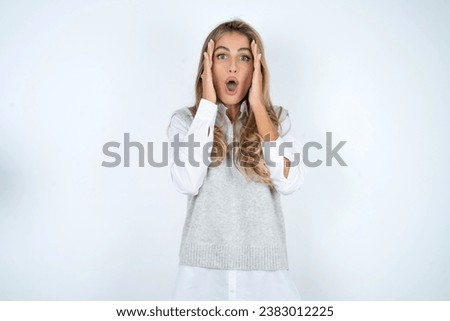 Young business woman wearing formal clothingwith scared expression, keeps hands on head, jaw dropped, has terrific expression. Omg concept