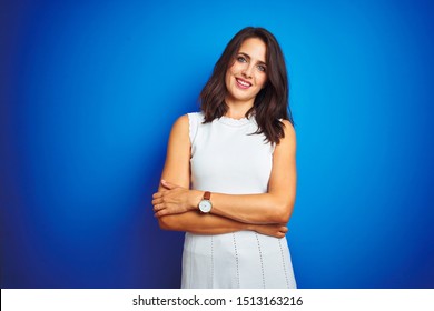 Young Business Woman Wearing White Elegant Dress Standing Over Blue Isolated Background Happy Face Smiling With Crossed Arms Looking At The Camera. Positive Person.