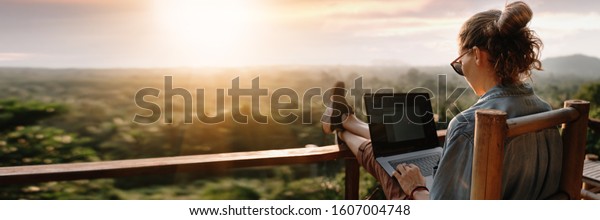 Young\
business woman working at the computer in cafe on the rock. Young\
girl downshifter working at a laptop at sunset or sunrise on the\
top of the mountain to the sea, working\
day.