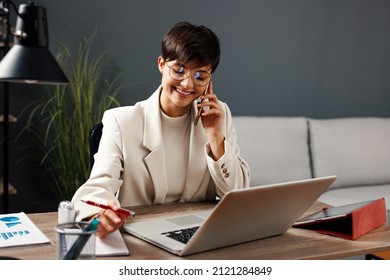 Young business woman working at home with laptop and papers on desk and talking on the phone - Shutterstock ID 2121284849
