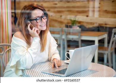 Young business woman working with laptop and mobile phone at cafe, freelance concept