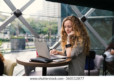 Young business woman with working with laptop inside coffee store. 