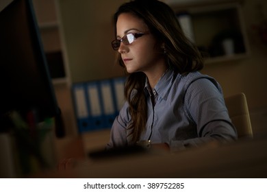 Young Business Woman Working Late In Office.She Works Late Into The Night Looking At Monitor.