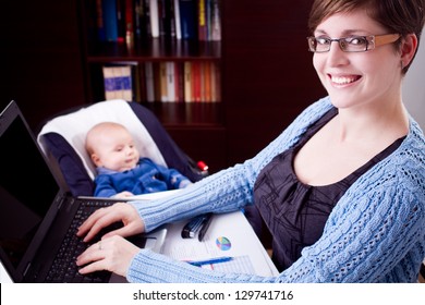 young business woman working on a laptop with her baby in the background