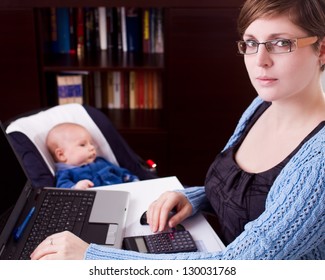 young business woman working on a laptop with her baby at the back