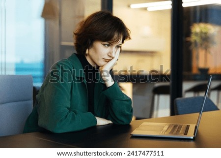 Young business woman working on laptop. Flexible office for startups. Fatigue female looking into the computer at Working space. Small online tired business owner. Problems at work