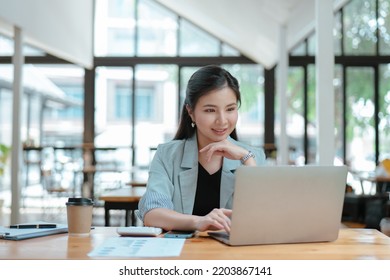 Young business woman working and typing on laptop with happy and smile face on office space. - Shutterstock ID 2203867141