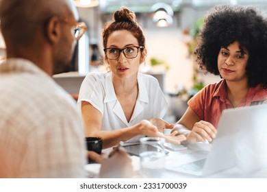 Young business women engaging in a discussion with a work client in a café, sharing their ideas and expertise. Male and female entrepreneurs having an informal meeting, planning a collaboration. - Powered by Shutterstock