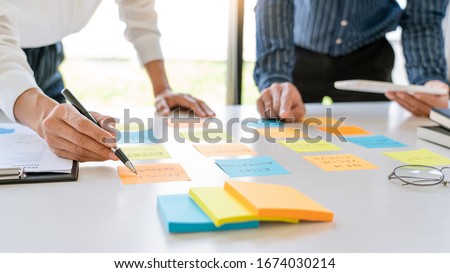 young business workers posting with sticky notes stickers reminders  creative brainstorming at board the colleague in a modern co-working space