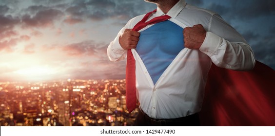 Young businessman acting like a superhero and tearing his shirt off over the city at the sunset with copy space 