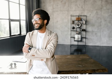 Young businessman in a beige suit strikes a pose with his arms confidently crossed, reflecting a persona of determination and professionalism. Male office employee looking aside with smile - Powered by Shutterstock