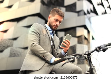 Young businessman with bicycle and smartphone on city street. - Powered by Shutterstock