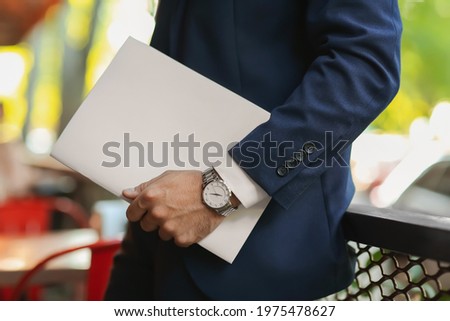 Young businessman with blank magazine outdoors