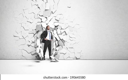 Young businessman breaking trough a wall