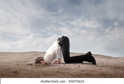 Young businessman burying his head in the sand